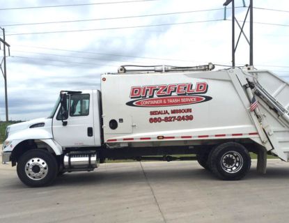 A Ditzfeld container and trash service truck parked in a lot