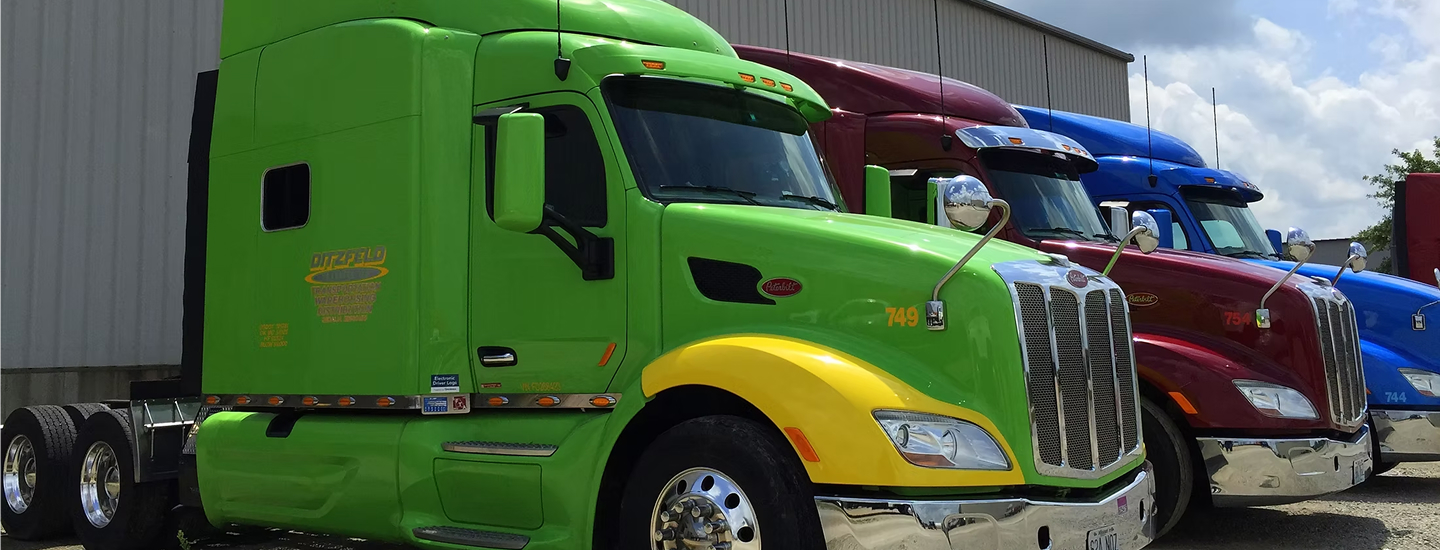 Three Ditzfeld semi trucks parked outside a warehouse