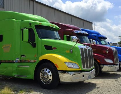 Three Ditzfeld semi trucks parked outside a warehouse